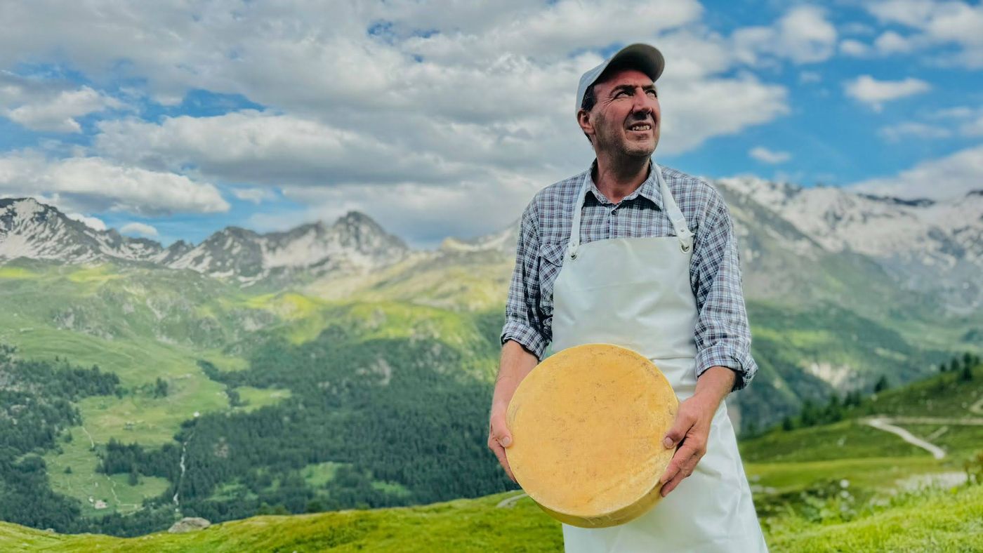 Casaro con una forma di Fontina DOP davanti alle vette dell'Alpeggio Arp Vieille